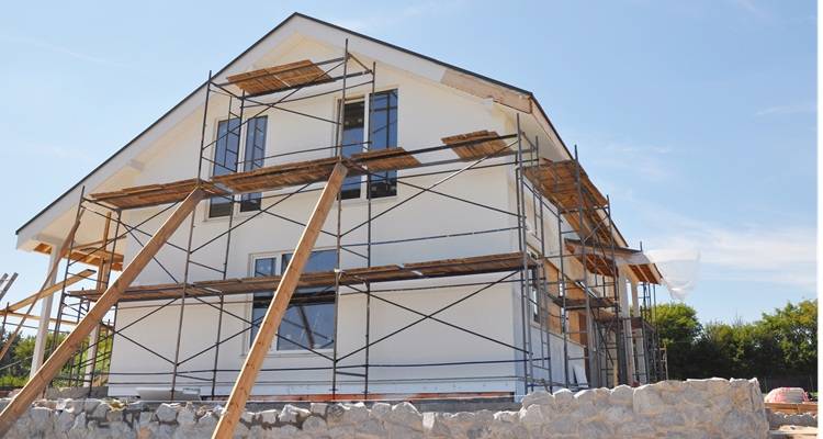 cream house with scaffolding round it