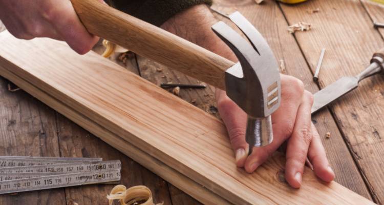 someone hammering nail into wood