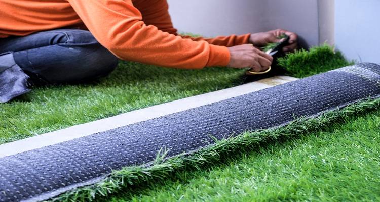 fake grass being cut against wall