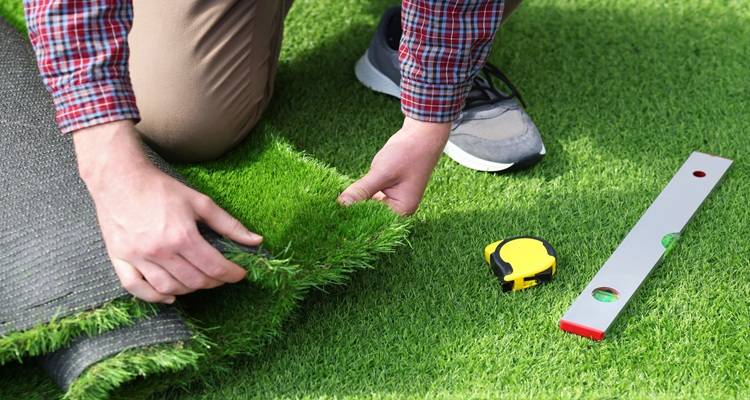 hands measuring for fake grass