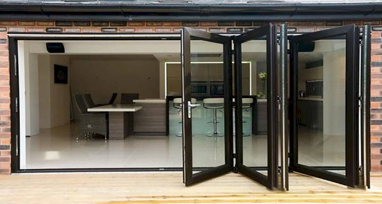 black bifold doors installation that lead into an open plan kitchen
