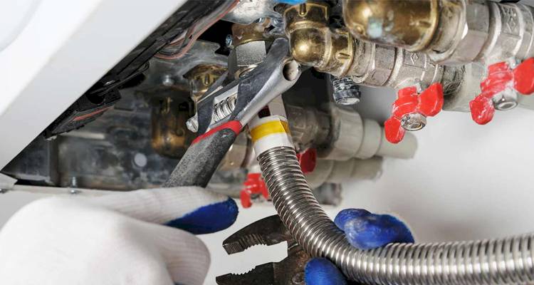 closeup of boiler piping being worked on by a person