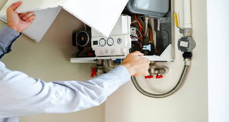 hands underneath boiler fixing it