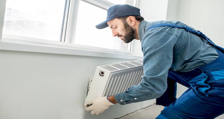 radiator being removed from a wall by a plumber