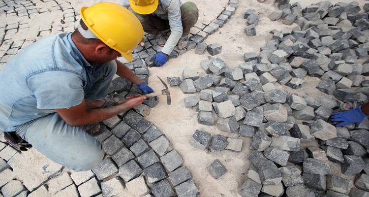 men laying cobblestones