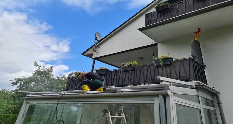 man on conservatory cleaning roof
