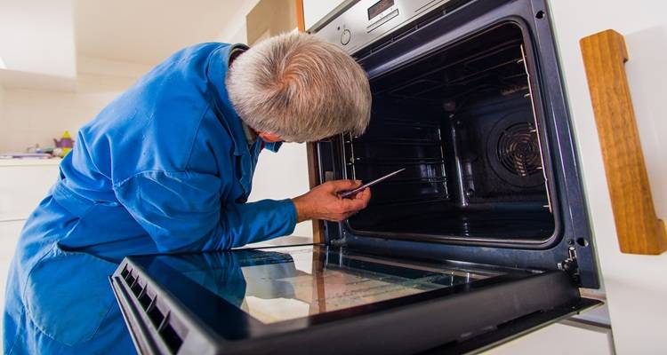 man blue looking in oven