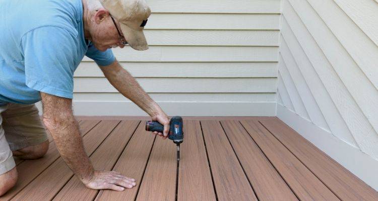 person using a drill to install composite decking