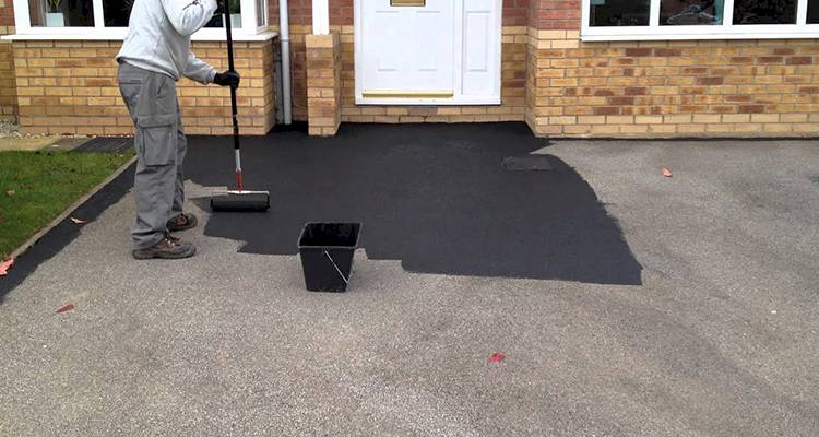 person working on a tarmac driveway in the UK