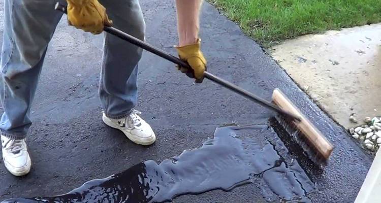 tradesperson resurfacing a tarmac driveway in the UK