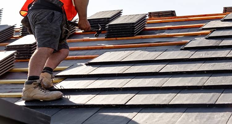 man orange vest laying tiles on roof