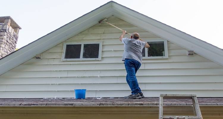 man cleaning soffits on porch