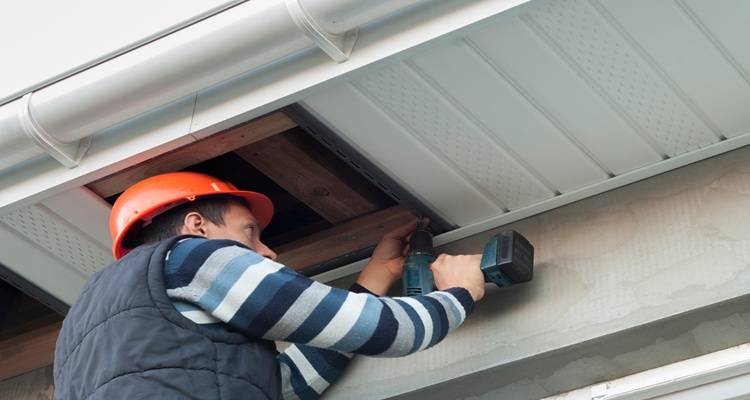 man screwing new soffits on