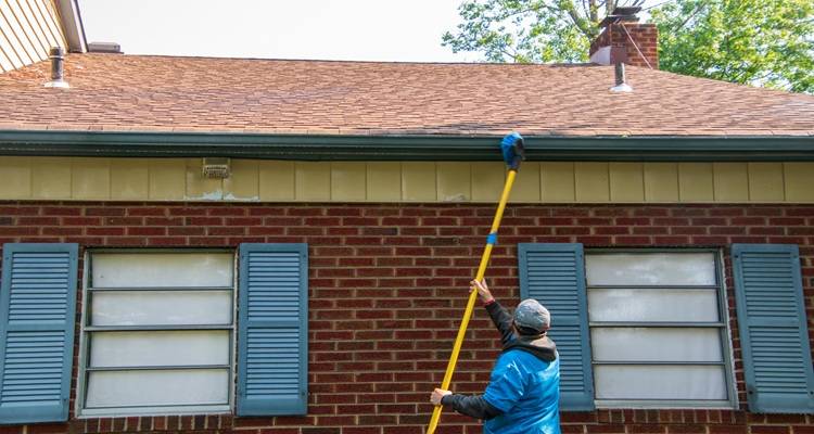 man brushing water fed system soffits