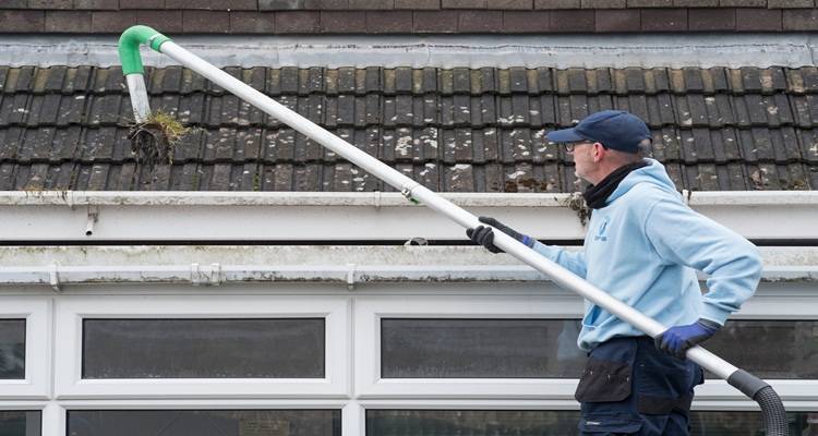 man sucking gutters out moss