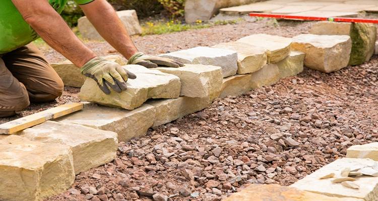 hands building garden cobblestone wall