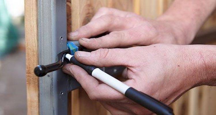 tradesperson fitting the locking mechanism on a new gate installation