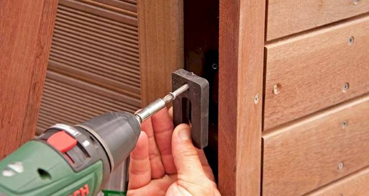 tradesperson using a drill to install a large gate in the UK