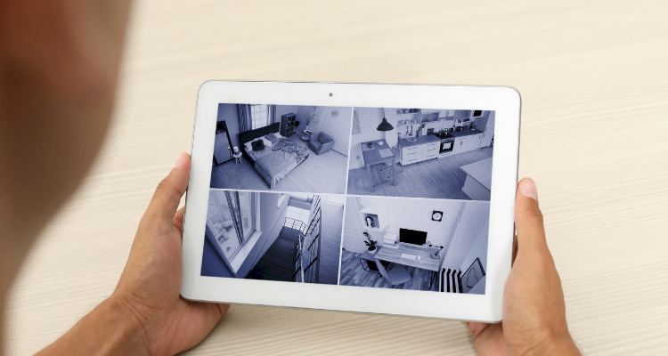 person holding a tablet with a 4-panel CCTV feed from their home