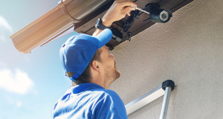 closeup of a tradesperson installing a CCTV camera and security light outside