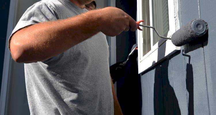 house extension cost guide &mdash; tradesperson painting the exterior of a house extension