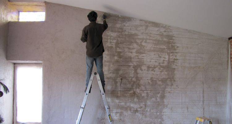 house extension cost guide &mdash; tradesperson plastering a wall