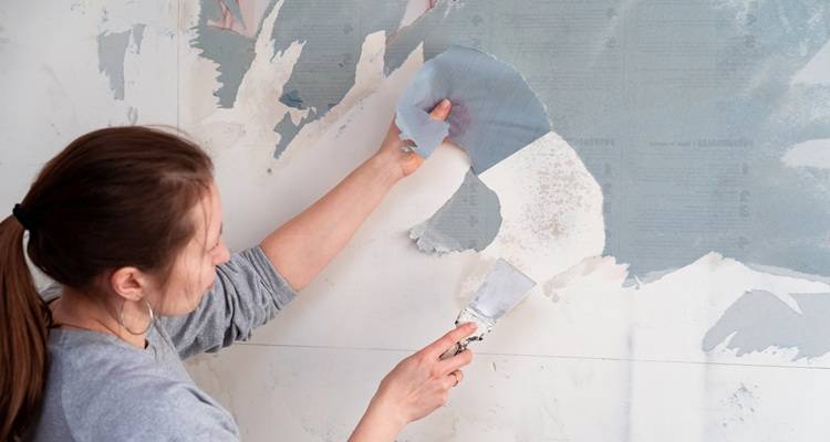 woman scraping wallpaper off
