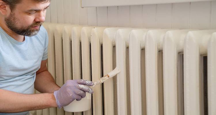 tradesperson painting a radiator in a hallway