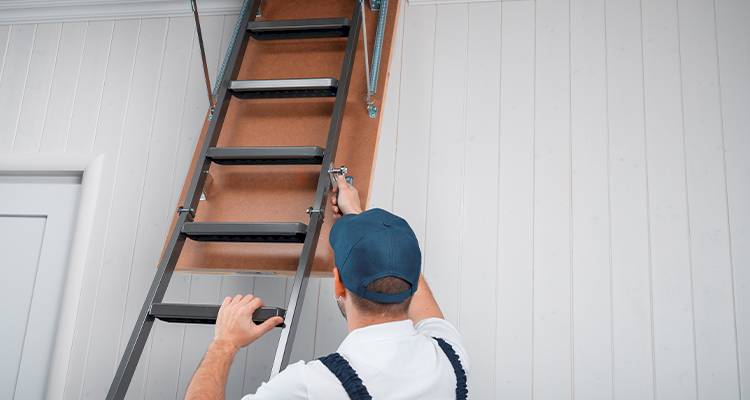 tradesperson accessing an attic space through a loft hatch