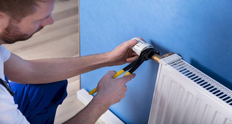 central heating installation cost guide &mdash; tradesperson fitting the valve on a radiator
