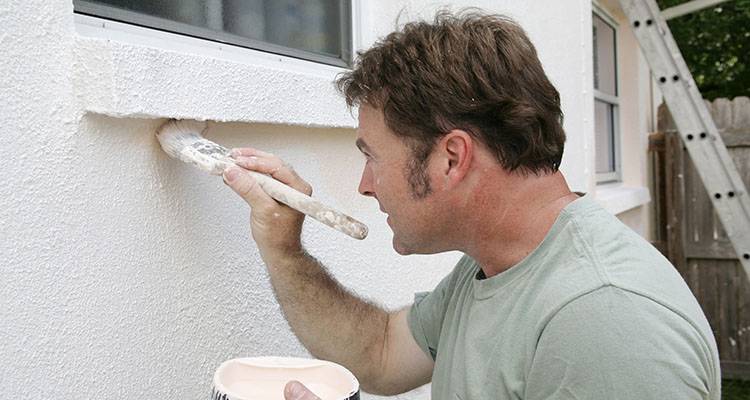 man painting the exteripr of a house
