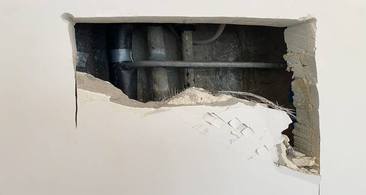 hole in wall showing pipes