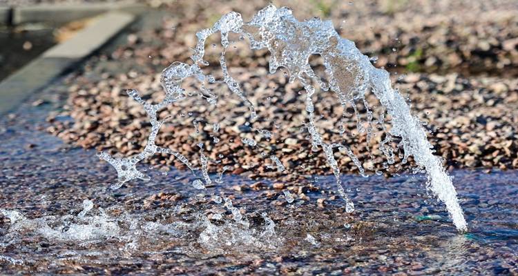 water leak spurting out of ground on gravel