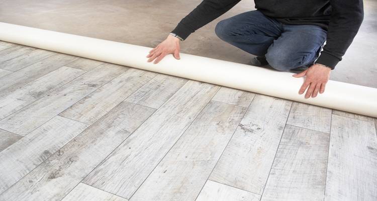 roll of lino being laid hands