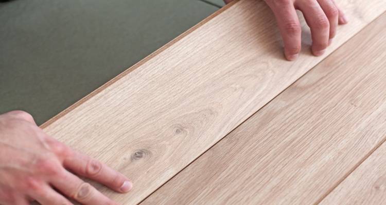 hands laying wooden flooring from above