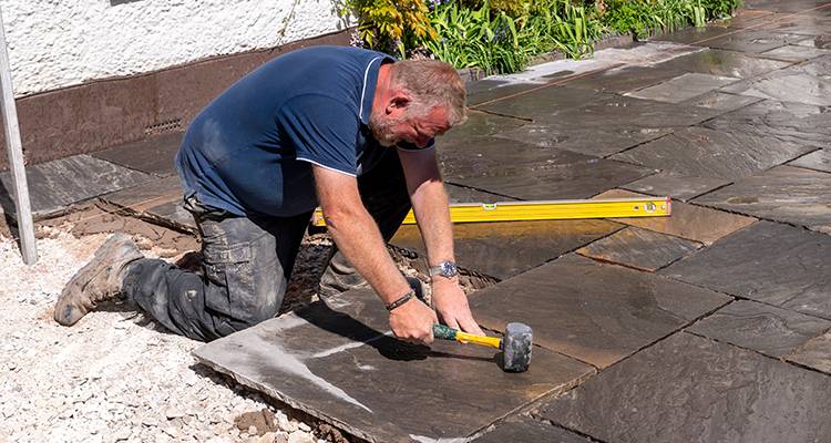 person laying patio slabs