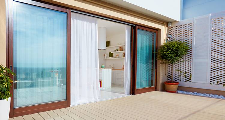 brown framed patio door that is opened and leading out to the exterior of home