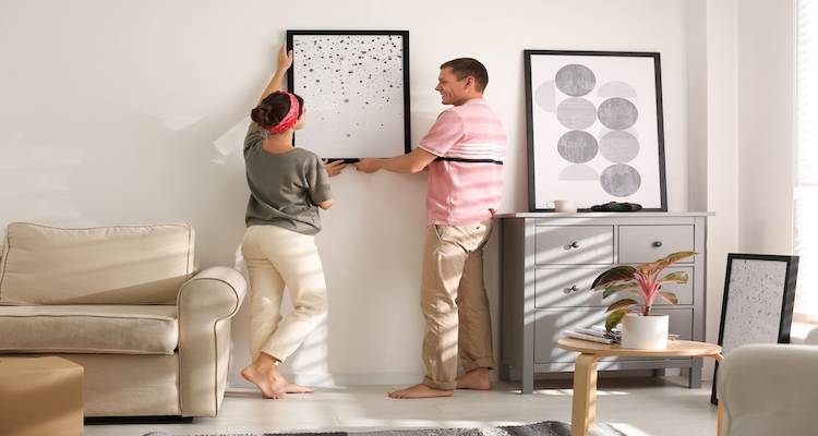two people hanging up a picture frame