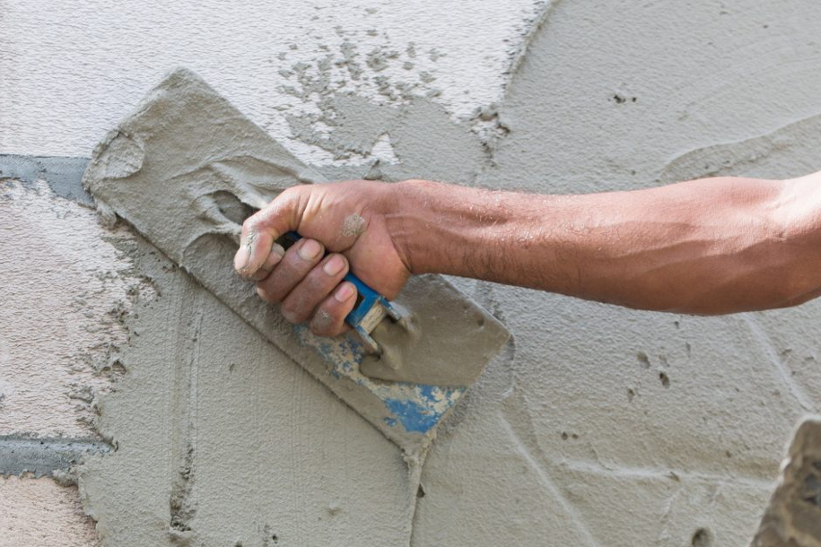 person plastering wall with trowel
