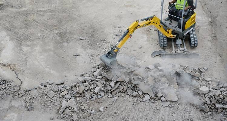 excavator digging up concrete