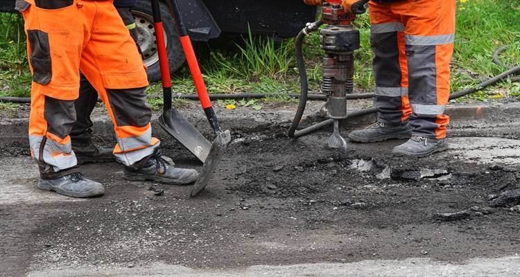 workers legs removing driveway