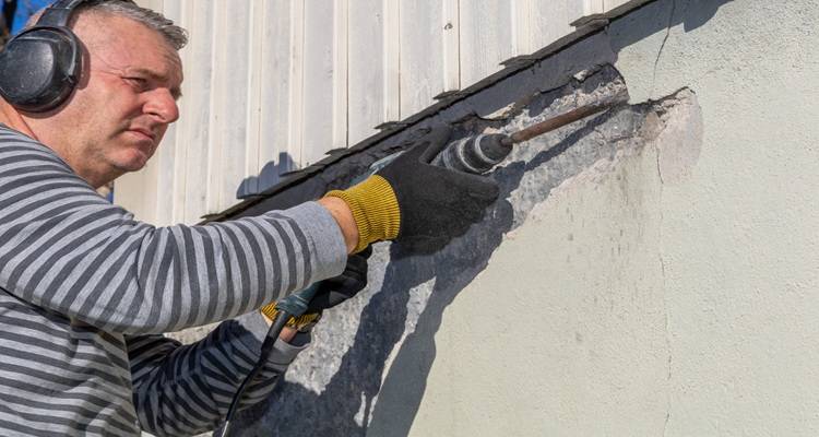 man removing render with SDS drill
