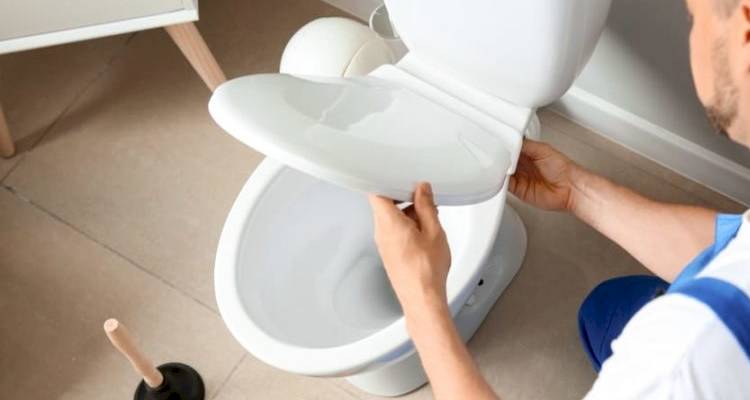 tradesperson adjusting the tightness of lid connection on a new toilet