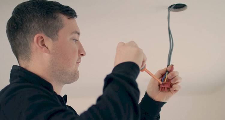 electrician that is wiring in a new ceiling lighting fixture
