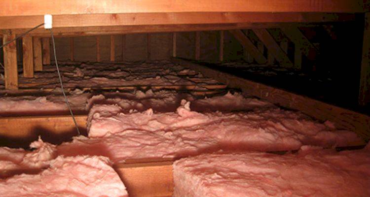 Tradesperson fitting roof insulation in a UK home