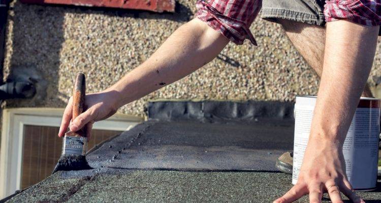 person doing some DIY roof maintenance on a flat roof in the UK