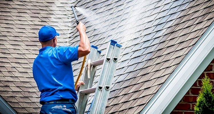 tradesperson applying a coating to a roof