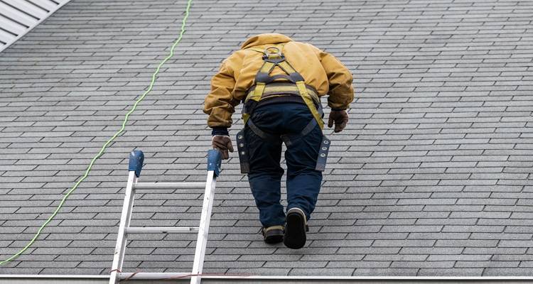man in yellow climbing on roof