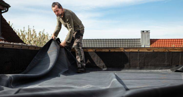 man laying rubber roofing sheets