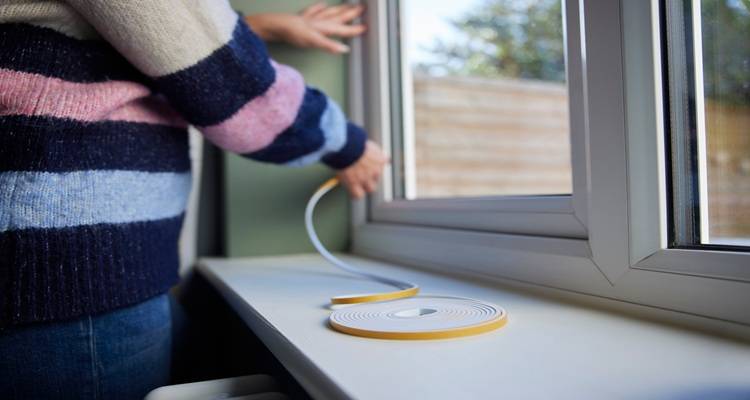 woman sealing around window stripey jumper
